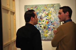 Painter Michael Stervinou talks to a guest about his painting at the opening of his art exhib at Agenda Loft