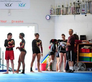 Coach Steven Marion with His Team During a Gymnastic Meet at Wilson H.S. L-R Nicole Mouser, Truman Wilson, Yajaira Moreno, Angela Boyes (Photo by Kaylene Peoples)